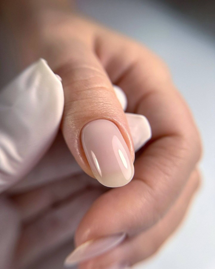 Close-up de unha com cutilagem limpa e esmaltação nude brilhante